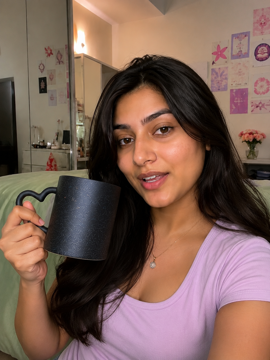 A woman holds up a black heart- handled magic mug which was a customized gift in a brightly lit bedroom 